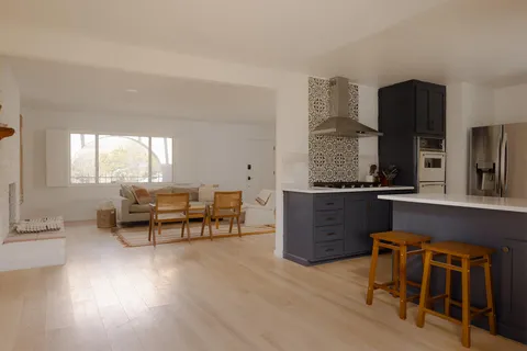 a living room with furniture a large window and wooden floor