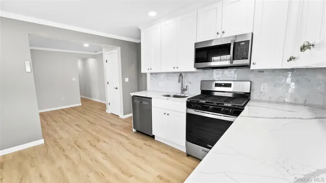 a kitchen with stainless steel appliances granite countertop a stove a microwave and a white cabinets