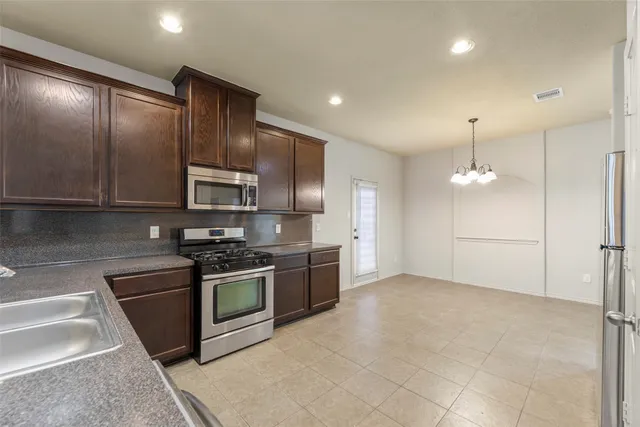 a kitchen with stainless steel appliances granite countertop a stove a sink and a refrigerator