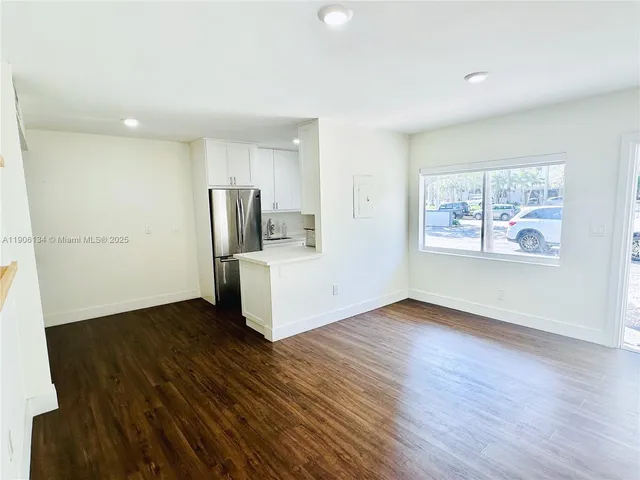 a view of a kitchen with wooden floor electronic appliances and window