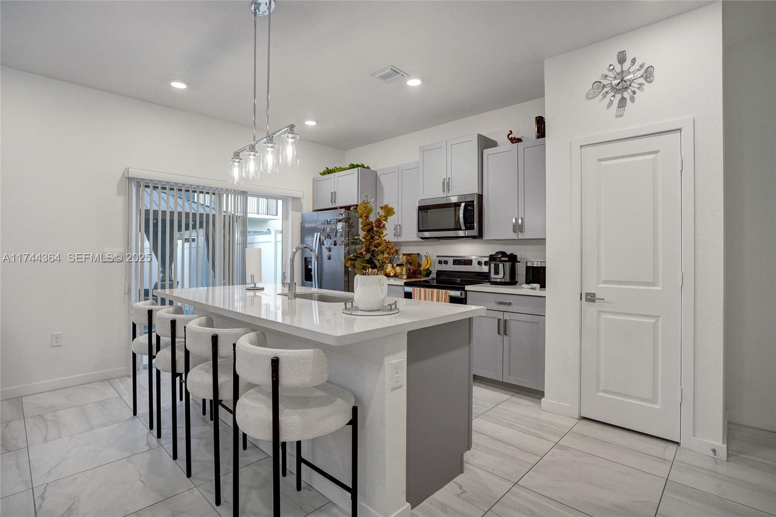 838 Southeast 17 Street Homestead, FL 33034 - Photo 12 of 66 a kitchen with kitchen island white cabinets and stainless steel appliances