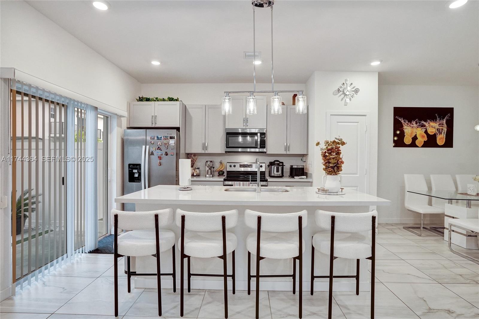 838 Southeast 17 Street Homestead, FL 33034 - Photo 15 of 66 a kitchen with stainless steel appliances kitchen island granite countertop a table chairs and a refrigerator