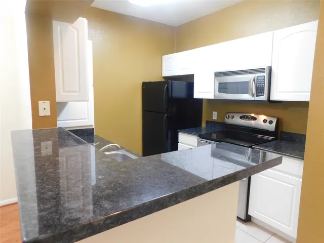 a kitchen with stainless steel appliances granite countertop a refrigerator and a stove