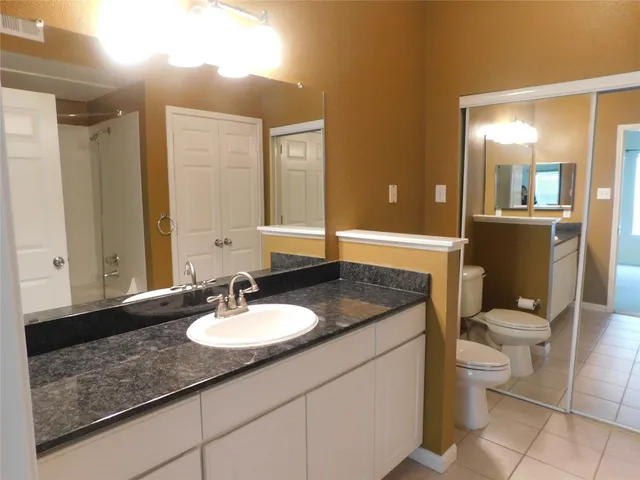 a bathroom with a granite countertop sink a toilet and a mirror