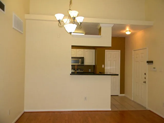 a view of a hallway with wooden floor and a chandelier