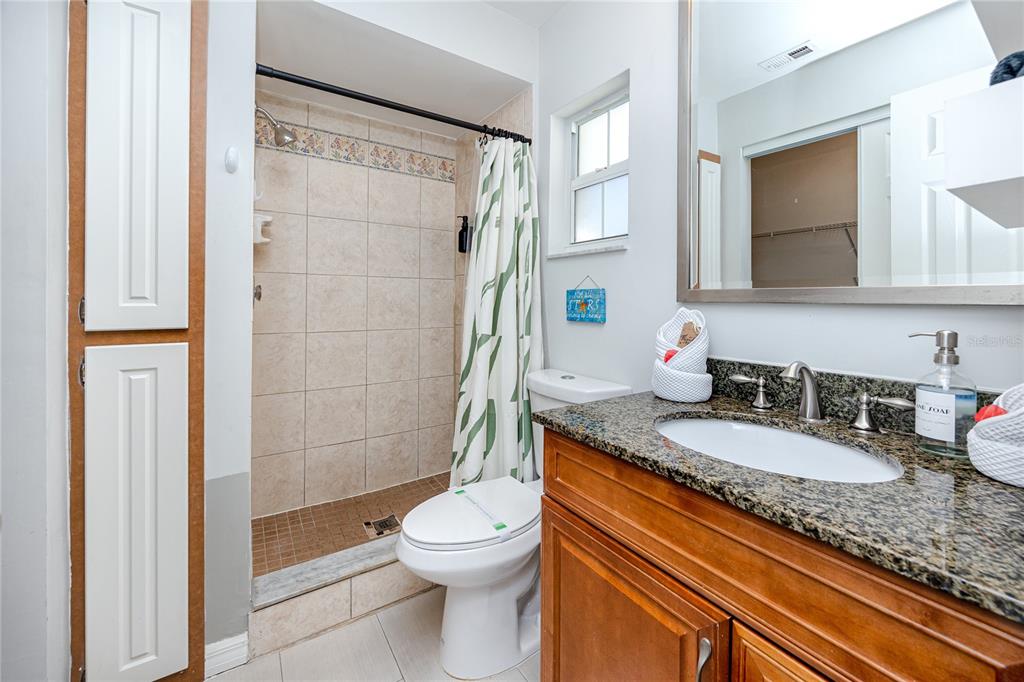 404 Maxwell Place Indian Rocks Beach, FL 33785 - Photo 19 of 66 a bathroom with a granite countertop sink a toilet a mirror and shower