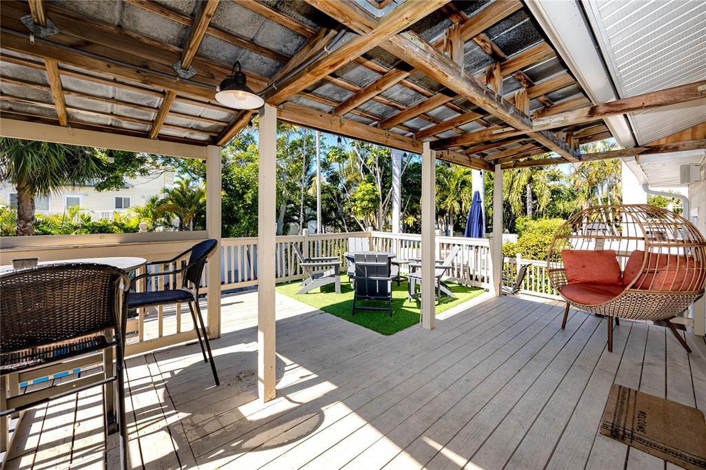 404 Maxwell Place Indian Rocks Beach, FL 33785 - Photo 27 of 66 a view of a patio with table and chairs potted plants with wooden floor and fence