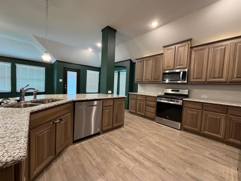 4420 Norcross Lane Crowley, TX 76036 - Photo 5 of 16 a large kitchen with granite countertop a stove top oven a sink dishwasher and wooden cabinets