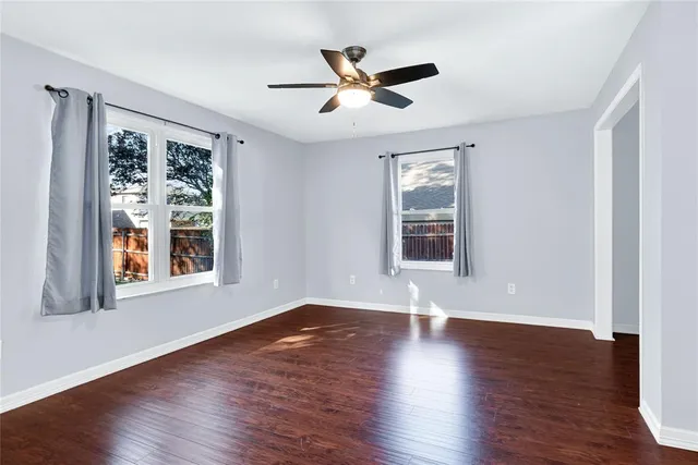 an empty room with wooden floor chandelier and windows