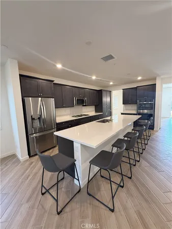 a kitchen with stainless steel appliances kitchen island granite countertop wooden floors and white cabinets