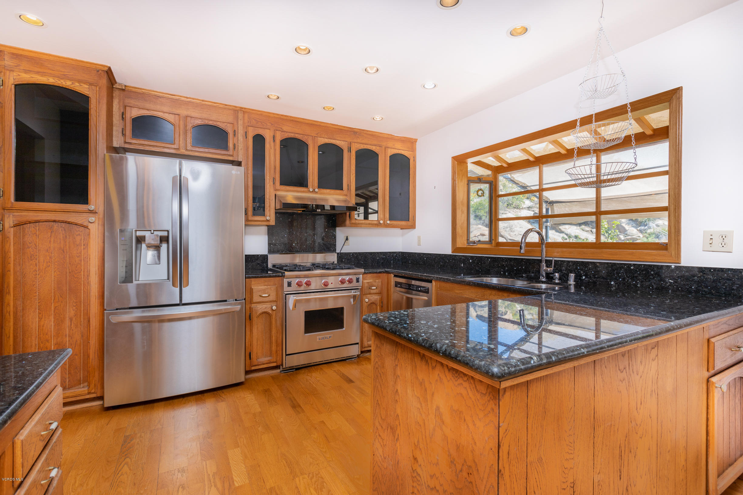 7240 Studio Road Canoga Park, CA 91304 - Photo 7 of 19 a kitchen with stainless steel appliances granite countertop a refrigerator a stove and a sink with wooden floor