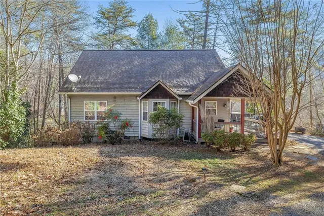 a view of a house with a yard and large tree