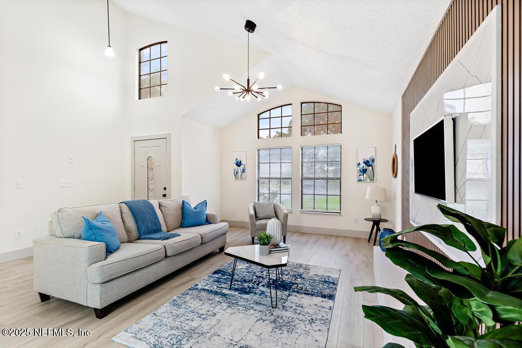 5497 Spring Brook Road Jacksonville, FL 32277 - Photo 8 of 54 a living room with furniture a chandelier and a flat screen tv