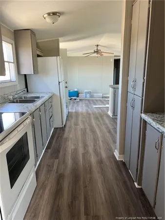 a kitchen with sink a refrigerator and wooden floor