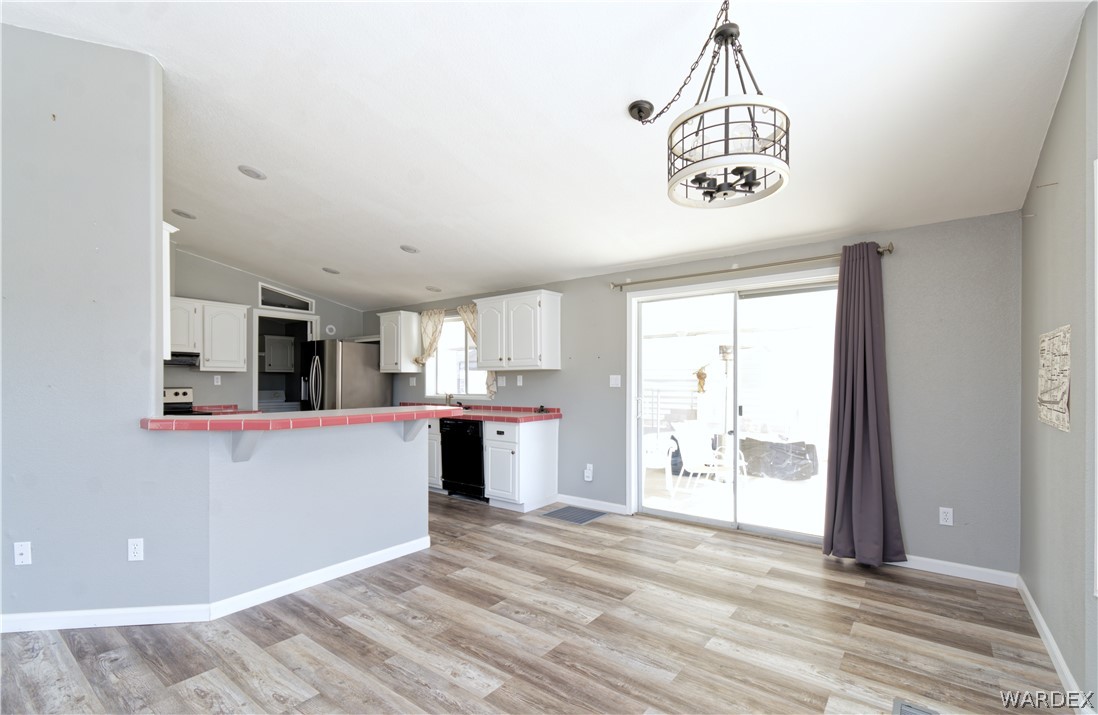 49603 Rainbow Avenue Quartzsite, AZ 85346 - Photo 10 of 44 Kitchen featuring tile countertops, lofted ceiling, white cabinets, light wood-type flooring, and a peninsula