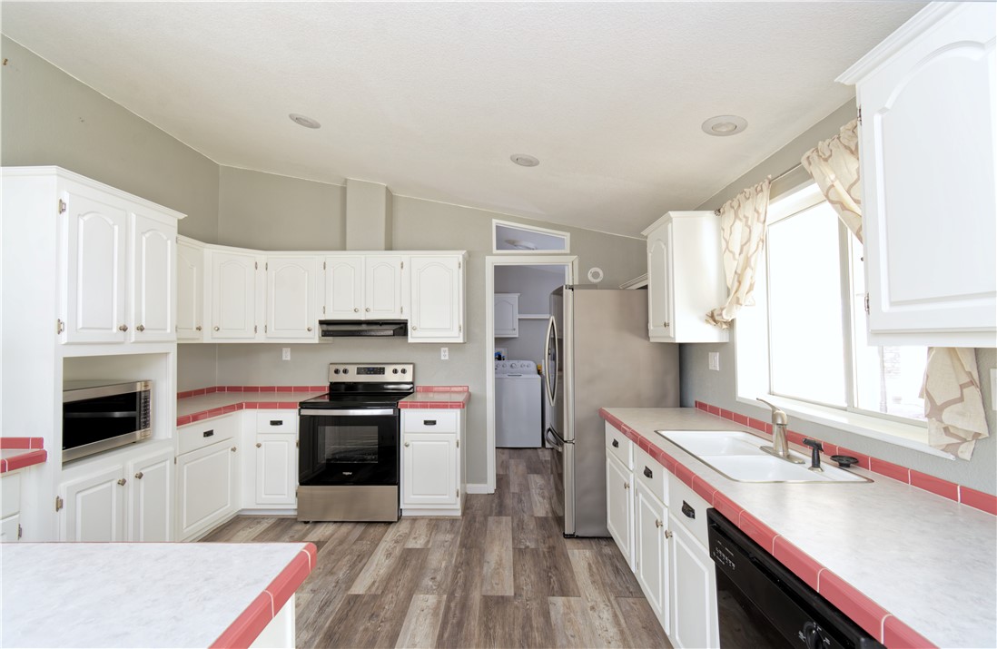 49603 Rainbow Avenue Quartzsite, AZ 85346 - Photo 12 of 44 Kitchen featuring white cabinets, stainless steel appliances, vaulted ceiling, washer / clothes dryer, and light wood-style flooring
