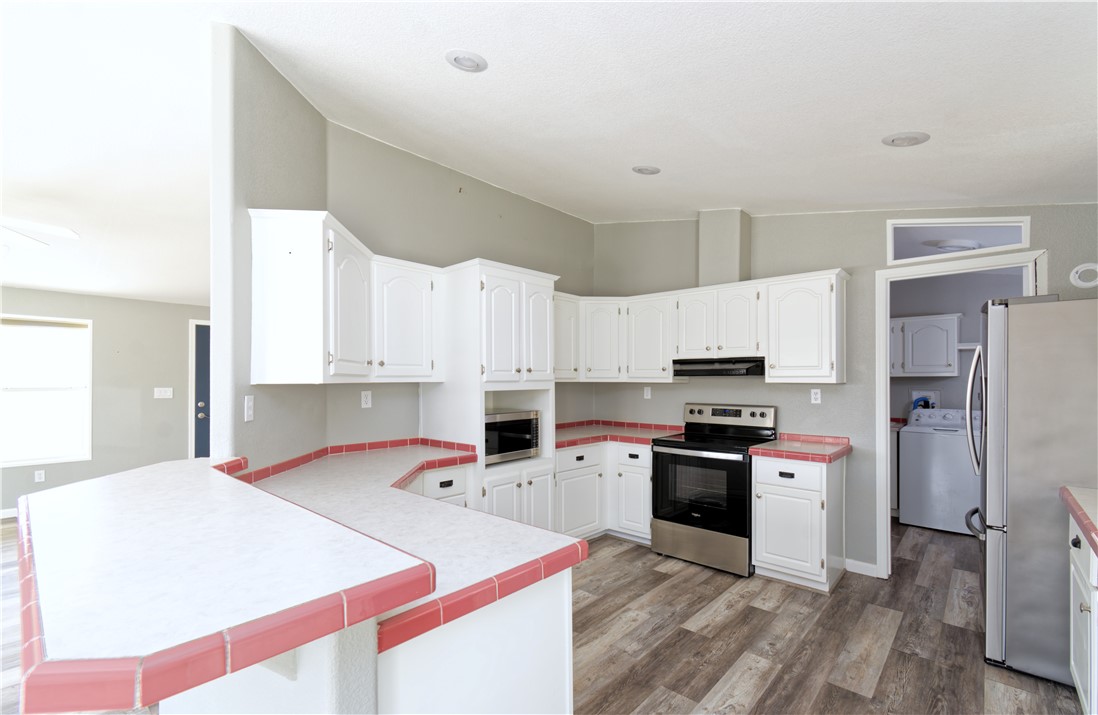 49603 Rainbow Avenue Quartzsite, AZ 85346 - Photo 15 of 44 Kitchen with stainless steel appliances, lofted ceiling, white cabinetry, light wood-type flooring, and a peninsula