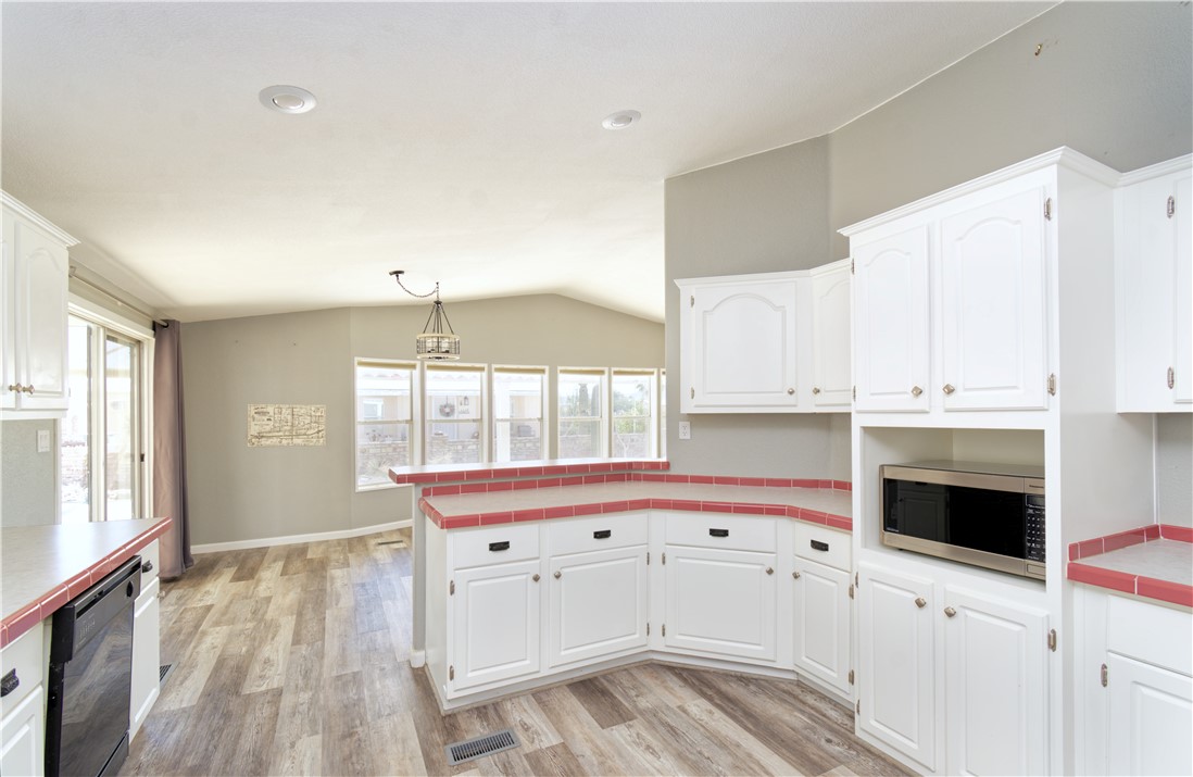 49603 Rainbow Avenue Quartzsite, AZ 85346 - Photo 17 of 44 Kitchen with tile counters, stainless steel microwave, white cabinets, dishwasher, and vaulted ceiling