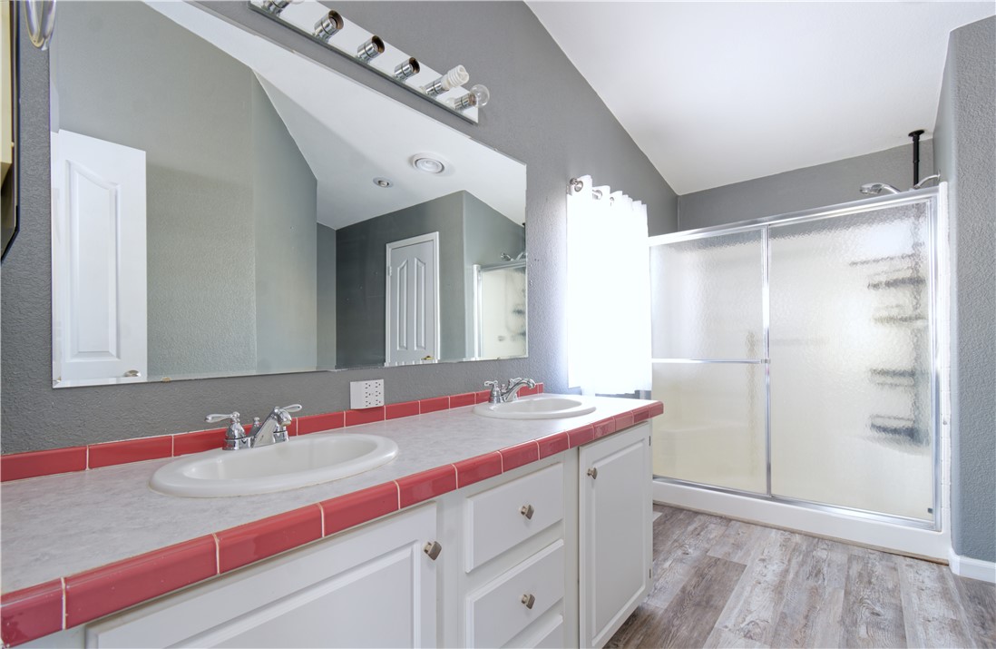 49603 Rainbow Avenue Quartzsite, AZ 85346 - Photo 22 of 44 Bathroom with a stall shower, double vanity, vaulted ceiling, and light wood finished floors