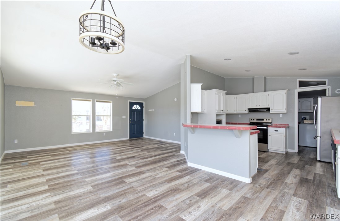 49603 Rainbow Avenue Quartzsite, AZ 85346 - Photo 44 of 44 Kitchen with white cabinetry, open floor plan, stainless steel appliances, light wood-style floors, and a breakfast bar