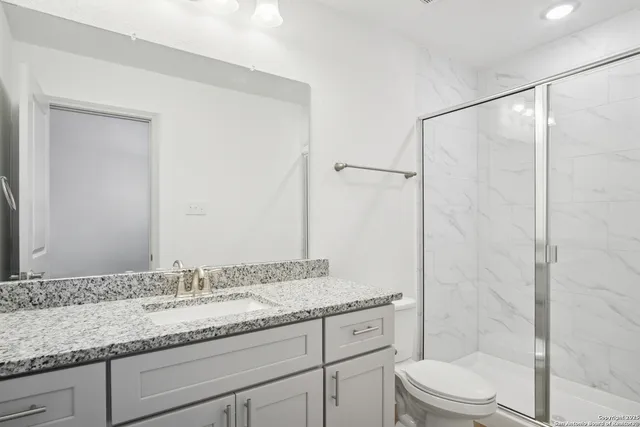 a bathroom with a granite countertop sink toilet and shower
