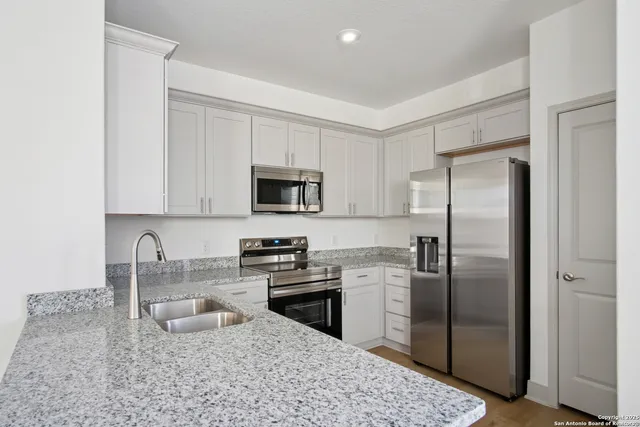 a kitchen with stainless steel appliances granite countertop a stove a sink a refrigerator a microwave and cabinets