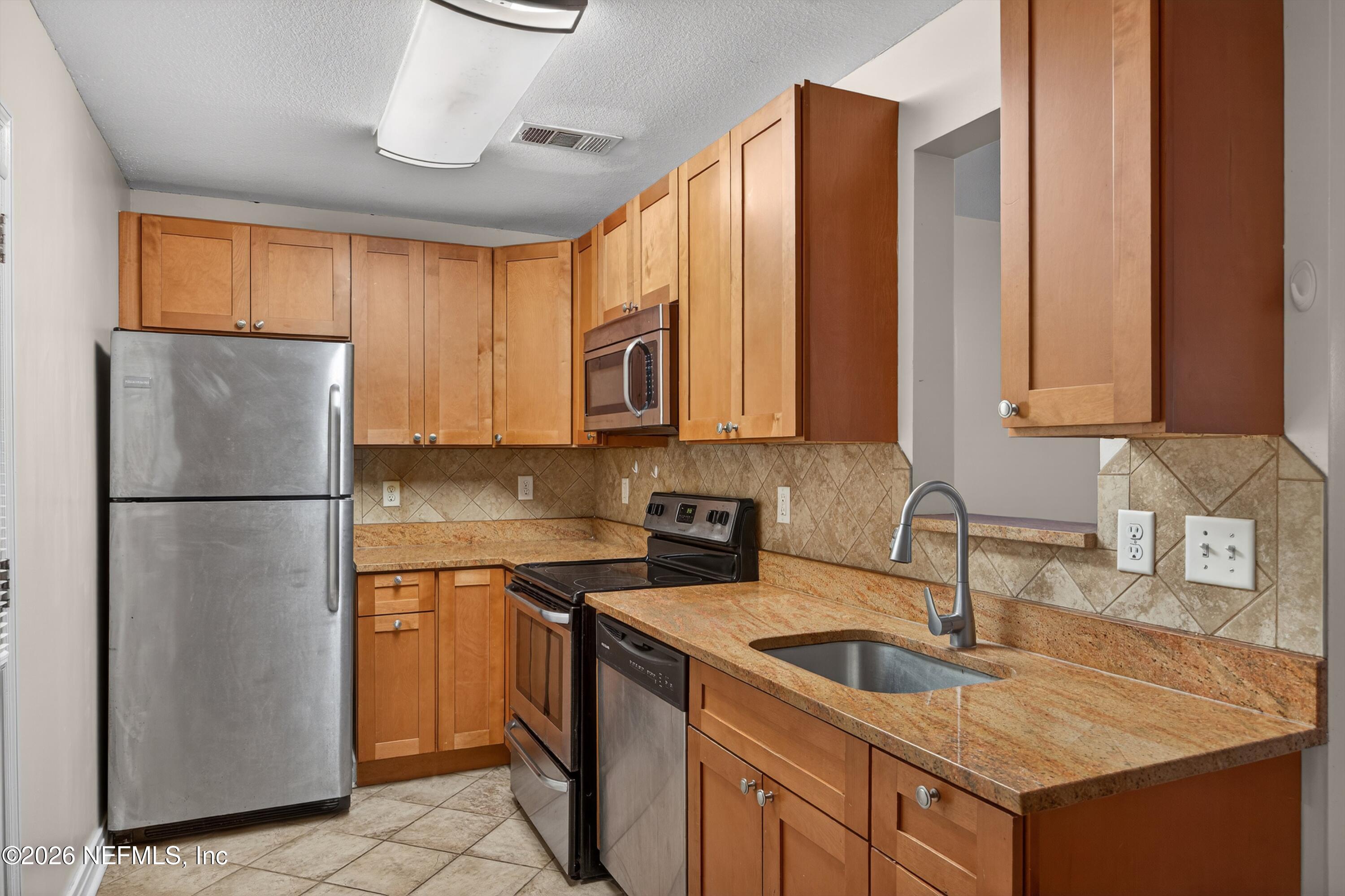 4231 Rendale Drive North Jacksonville, FL 32210 - Photo 11 of 37 a kitchen with a sink a refrigerator and cabinets