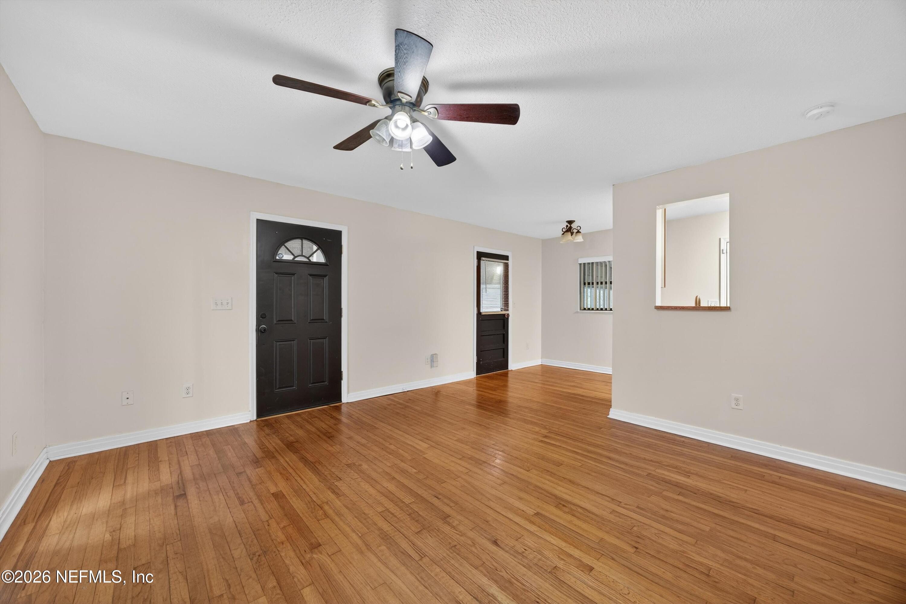 4231 Rendale Drive North Jacksonville, FL 32210 - Photo 8 of 37 a view of an empty room with wooden floor and a ceiling fan