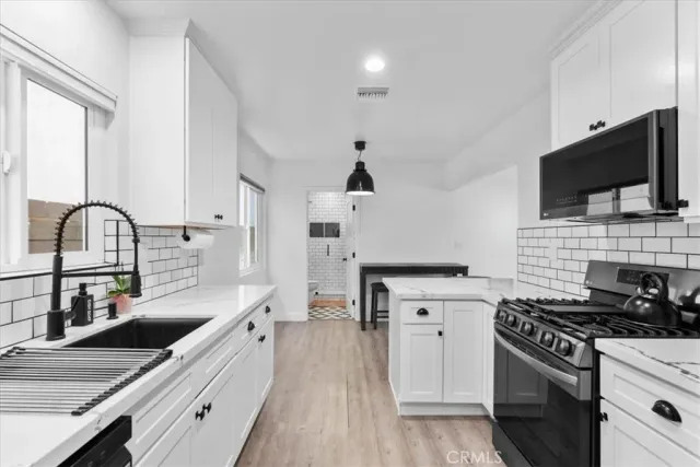 a kitchen with kitchen island granite countertop a sink appliances cabinets and a counter top space