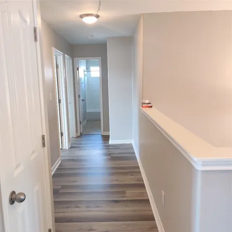 a view of a hallway with wooden floor and staircase