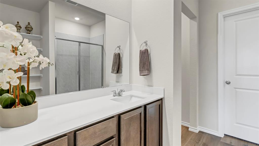 124 Pheasant Run Road Terrell, TX 75160 - Photo 25 of 35 Bathroom featuring a single vanity with a white countertop, dark wood-finish cabinetry, and a large mirror