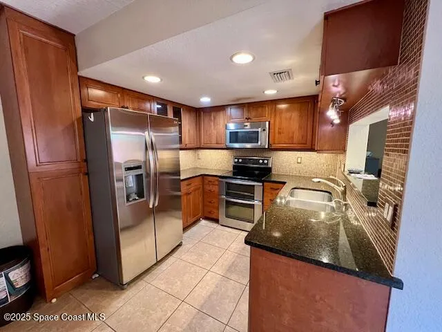 a kitchen with stainless steel appliances granite countertop a refrigerator a stove and a sink