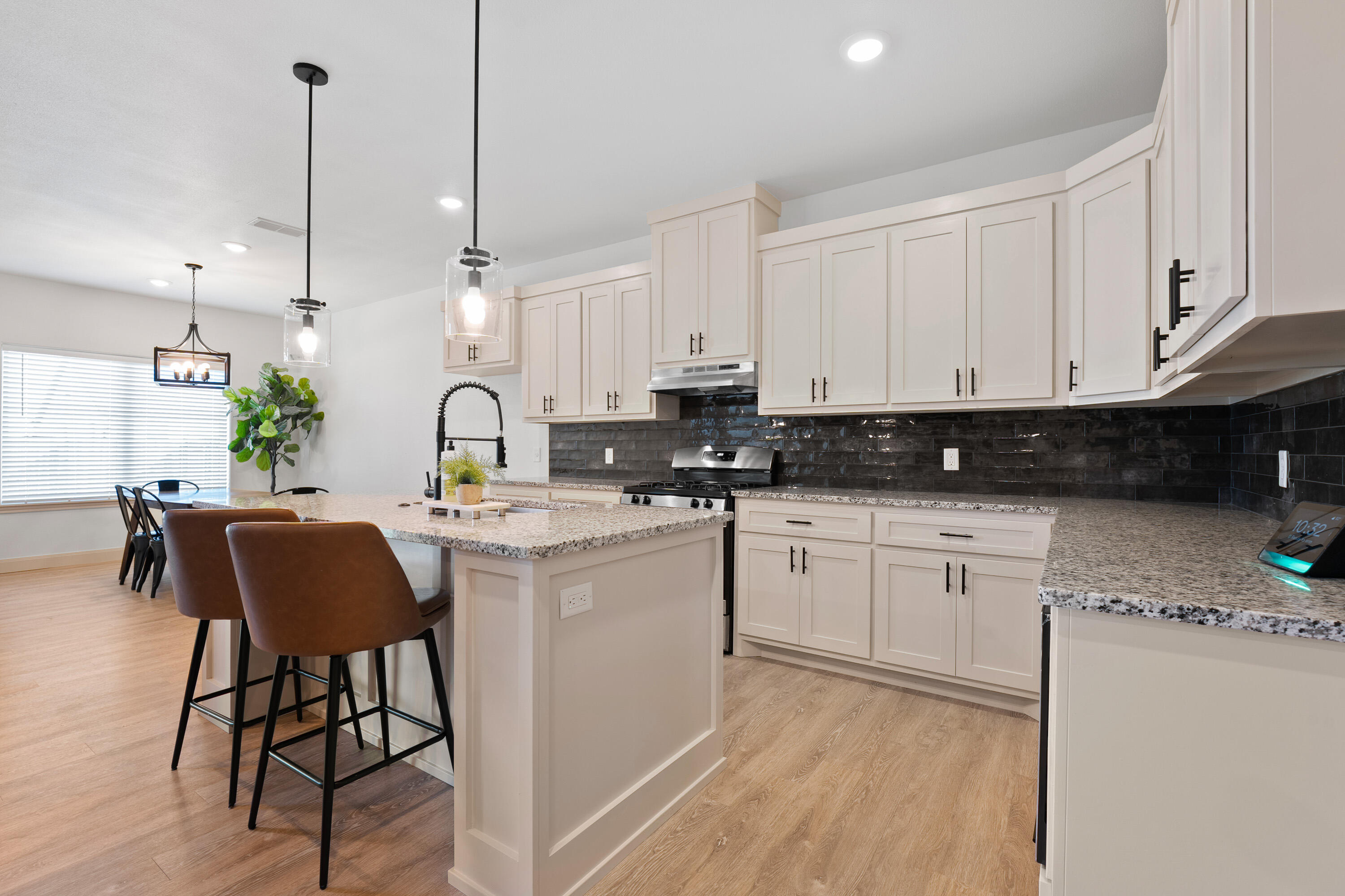 5516 120th Street Lubbock, TX 79424 - Photo 9 of 30 a kitchen with stainless steel appliances granite countertop a stove a sink a refrigerator a microwave a dining table and chairs with wooden floor