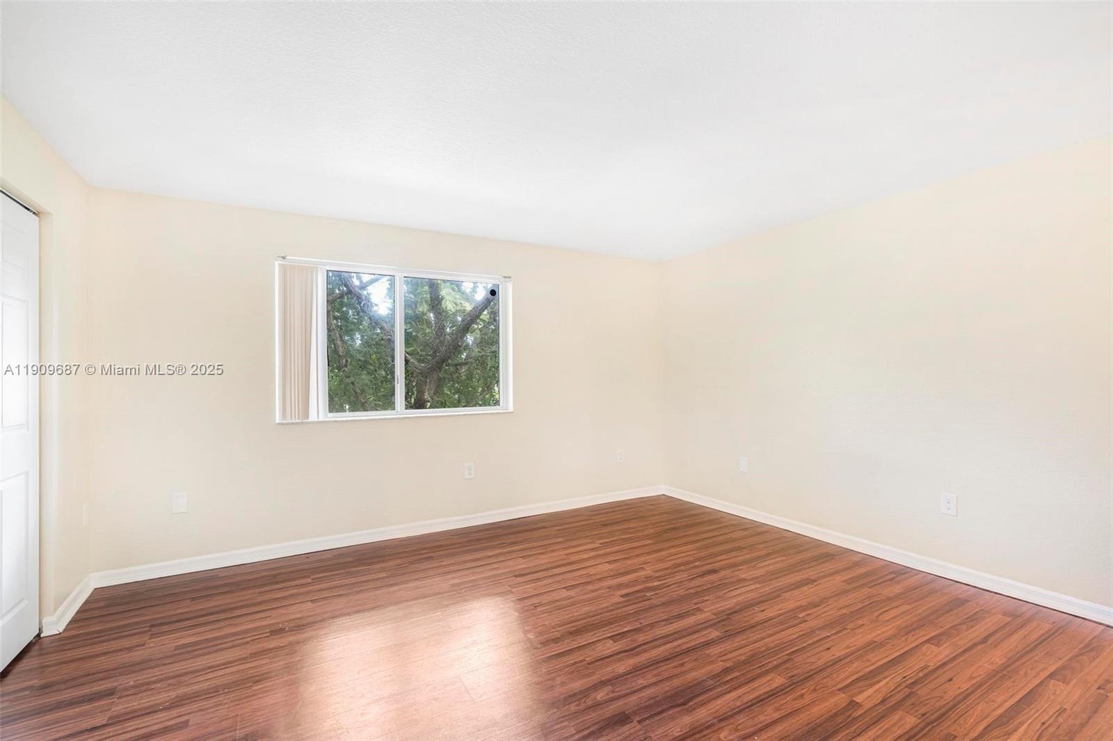 2261 Northwest 136th Terrace, Unit 2261 Opa-Locka, FL 33054 - Photo 11 of 19 a view of an empty room with wooden floor and a window