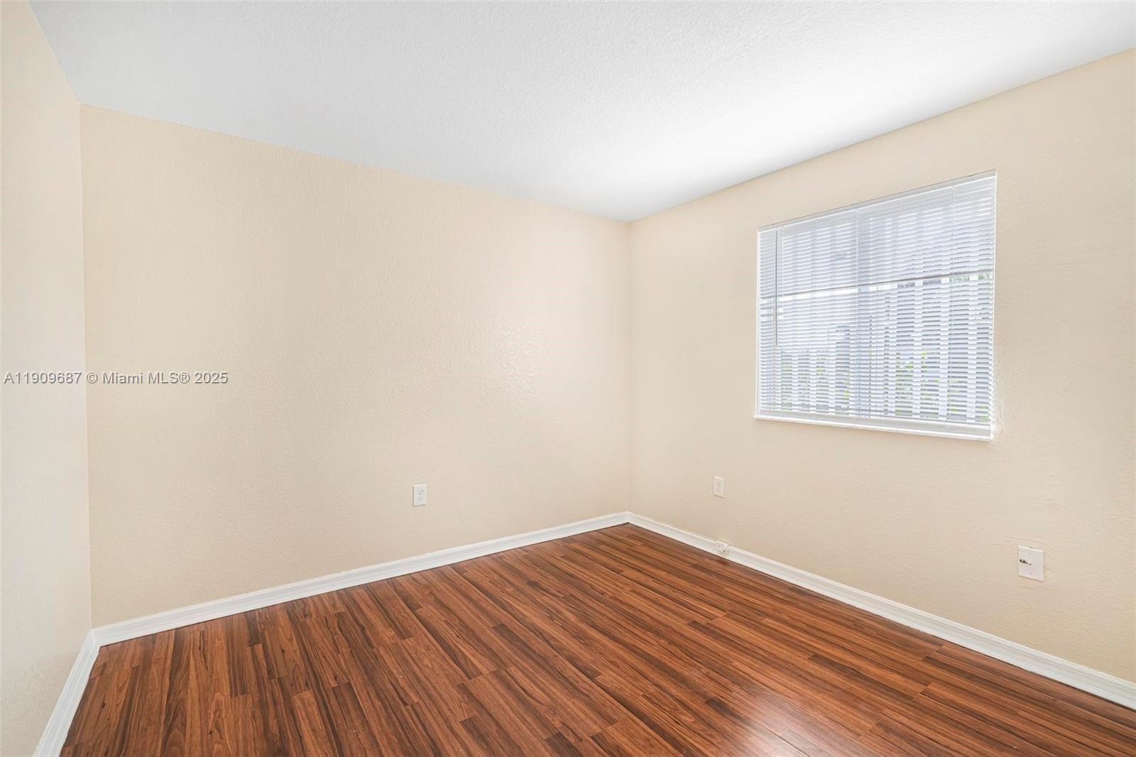 2261 Northwest 136th Terrace, Unit 2261 Opa-Locka, FL 33054 - Photo 14 of 19 a view of an empty room with wooden floor and a window