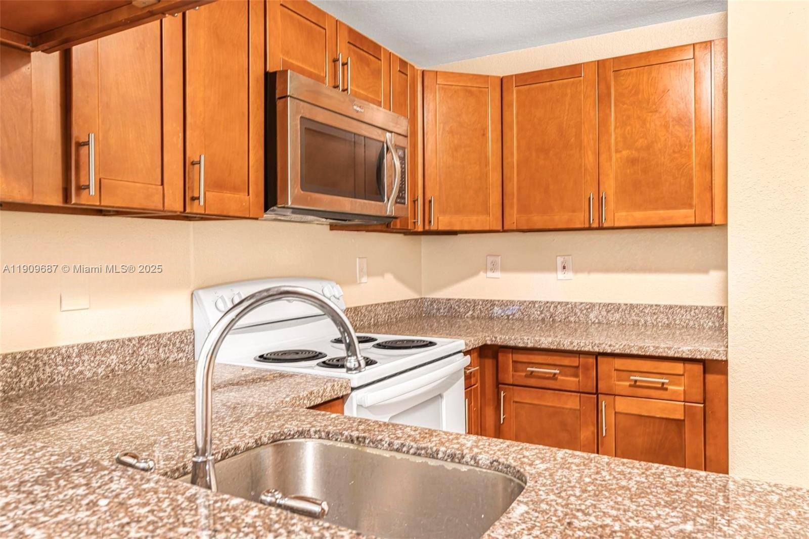 2261 Northwest 136th Terrace, Unit 2261 Opa-Locka, FL 33054 - Photo 7 of 19 a kitchen with stainless steel appliances granite countertop a sink a microwave cabinets and a counter top space