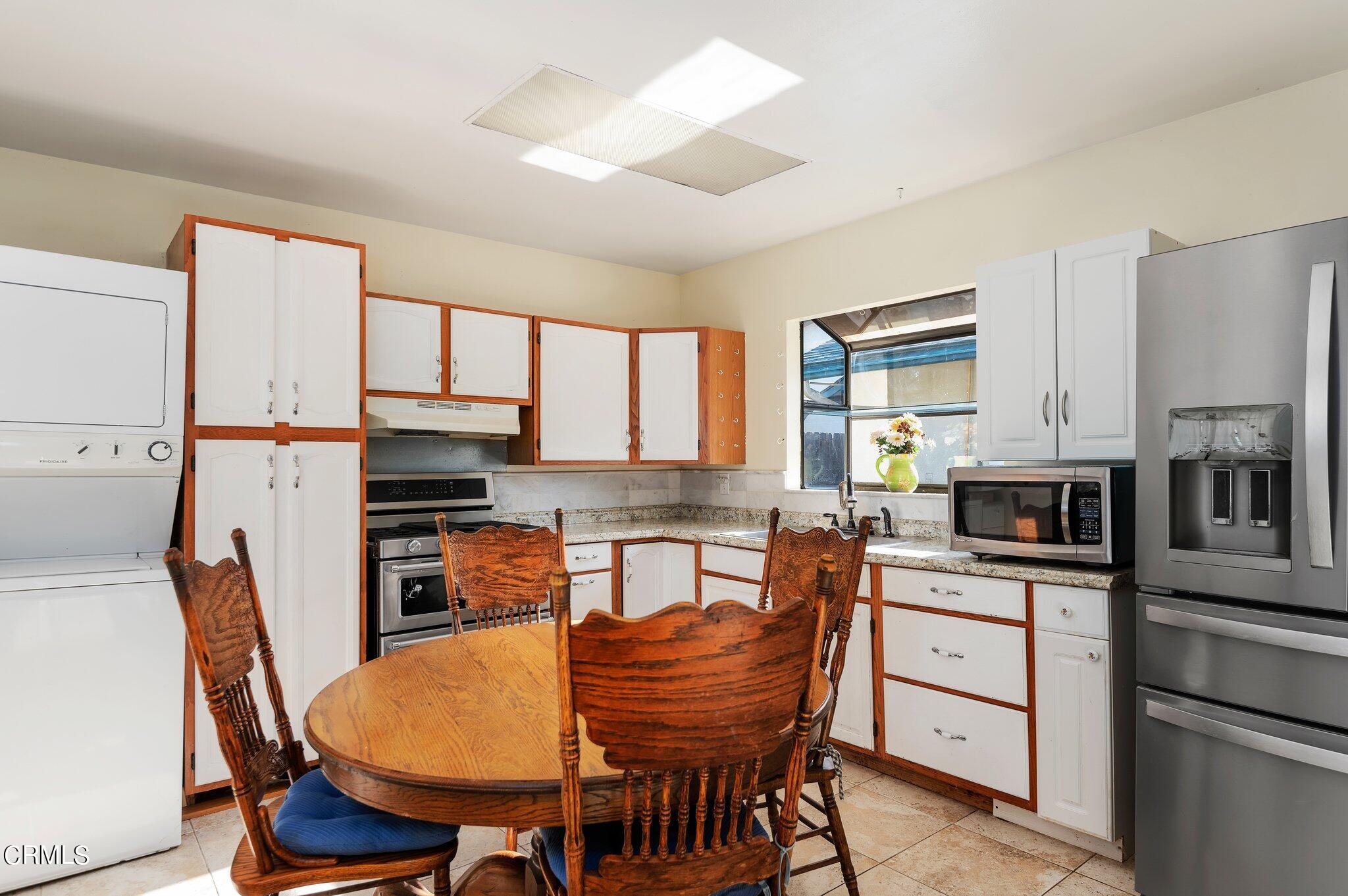 4810 Del Oro Place Oxnard, CA 93033 - Photo 18 of 21 a kitchen with stainless steel appliances granite countertop a stove a refrigerator a kitchen island a table and chairs