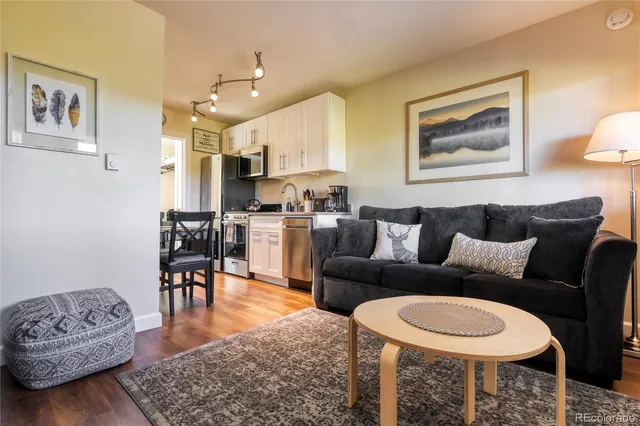 a living room with furniture a rug and kitchen view