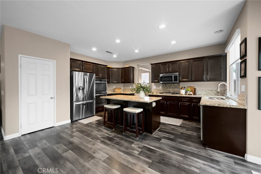 7220 Cumberland Place Rancho Cucamonga, CA 91739 - Photo 13 of 41 Chef-inspired kitchen featuring espresso cabinetry, granite countertops, stainless steel appliances, a large center island, and large walk-in pantry.