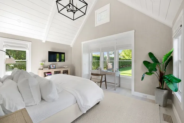 a bedroom with a bed and a potted plant on the dresser