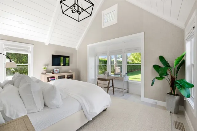 a bedroom with a bed and a potted plant on the dresser