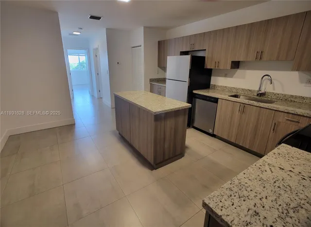 a kitchen with stainless steel appliances a refrigerator a stove a sink a microwave and island