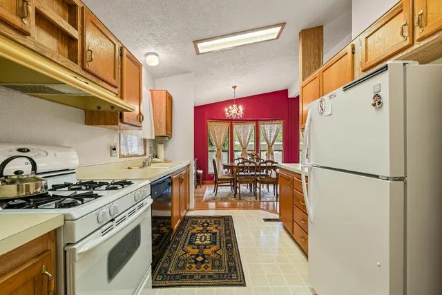 a kitchen with stainless steel appliances granite countertop a refrigerator a stove and a dining table with wooden floor