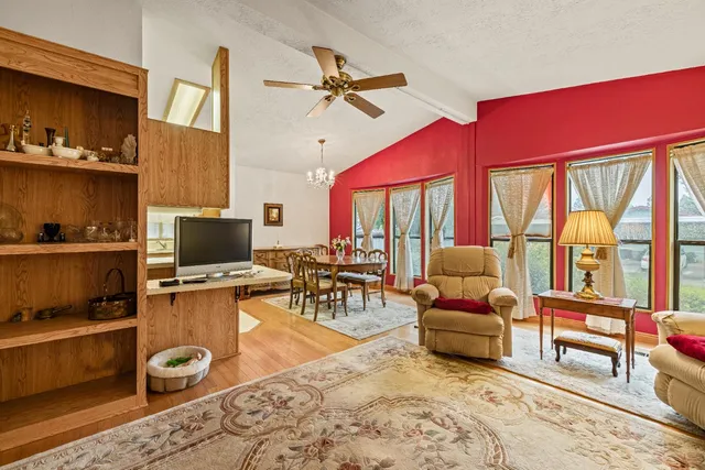 a living room with furniture a flat screen tv and floor to ceiling window