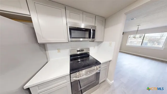 a kitchen with granite countertop a stove and a microwave
