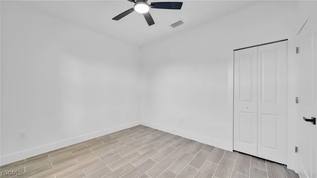 an empty room with a ceiling fan and wooden floor