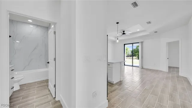 a view of a hallway with wooden floor and a bathroom