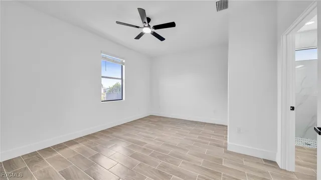 an empty room with wooden floor a ceiling fan and windows