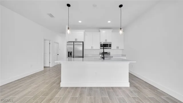 a view of kitchen with stainless steel appliances granite countertop a sink a refrigerator and a stove