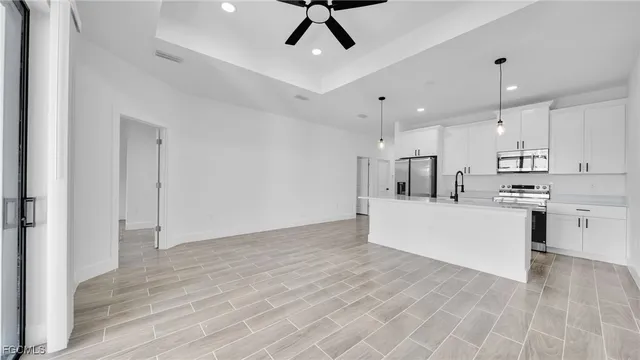 a view of kitchen with stainless steel appliances refrigerator oven microwave and white cabinets